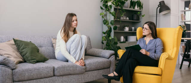 A depressed woman patient is sitting on the couch telling a psychologist