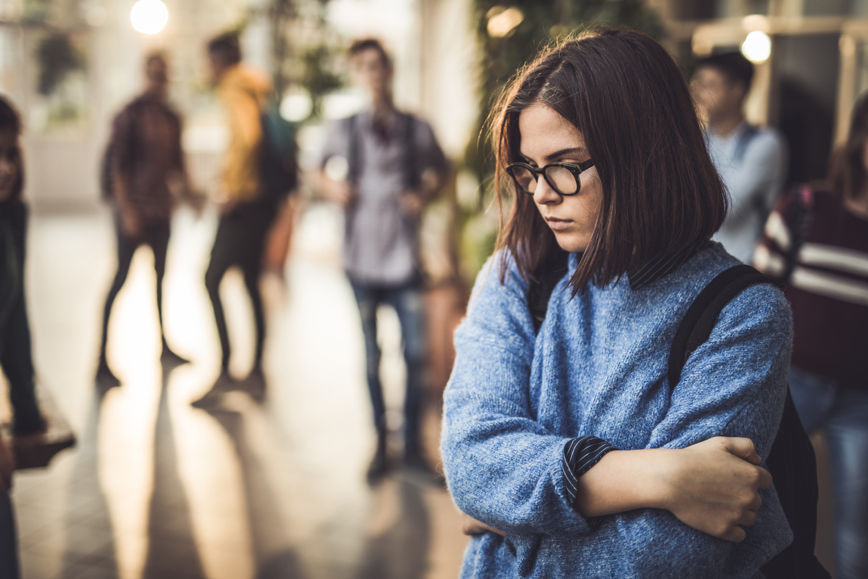socially anxious teen standing alone away from other teens